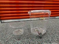 Full view of the clear plastic water dispenser jug showing its hexagonal shape, removable lid and metal spigot at bottom.