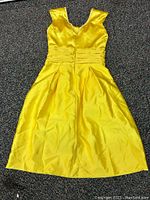 Photo of yellow women's dress laid flat, showing front with v-neck, pleated waist, and flared skirt.