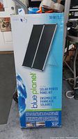 Front of the original box showing the 30W/2A Blue Planet Folding Solar Power Panel Kit with Earth graphic and branding.
