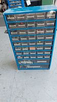 Front view showing 43 clear plastic drawers in blue metal cabinet containing various hardware items.