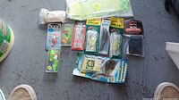 View of assorted new fishing lures and gear in original packaging on surface with shoes visible for scale.