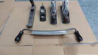 Photo shows four wood planes and a metal rasp file arranged on cardboard.