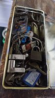 Metal container filled with assorted vintage keys, key chains, and few padlocks