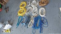 Various coils of rope in different colors and materials spread on a floor