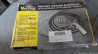 Front of box showing product name and image of sand blaster gun with nozzle and accessories with yellow description panel