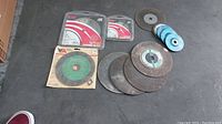 Lot of various grinding and cutting wheels on dark surface showing overall condition and quantity