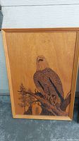 Full view of the framed wood carving showing an eagle sitting on a tree branch.