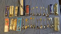 All collectible spoons laid out on a flat surface showing the full set with some spoons still in packaging.