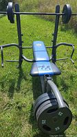 Front view of the weight bench with barbell loaded on rack set up outdoors on grass.
