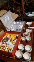 Overview photo showing two boxed Asian tea sets, cups, bowls, and teapots.
