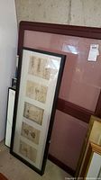 Framed quartert display case leaning against wall with no visible keys, wood frame dark finish, large size