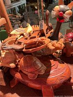 Photo showing various carved wooden animal figurines including turtle, crab, bird, a black cat with whiskers, and partial pig figurine.