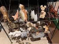 Wide view of metal rack with assorted animal figurines made of stone, metal, and glass.