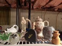 Wide view of shelf showing collection including white ceramic swan figurine, St Francis figurine, Wood's Burslem oriental tea pot, candle holder, glass paperweights, and jar