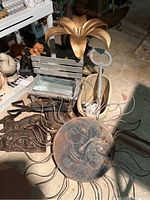 Photo showing metal sun wall art, key, flower sculpture, and various metal garden items including animal molds and tongs.