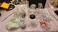 Photo showing entire collection of glass items including vases, jars with stoppers, bowls and canisters on a table.