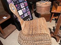 Side view of woven grass rocking chair showing woven weave, seat, curved rocker base, and loop handle back.
