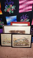 Five framed wall art prints arranged on the floor, showing historic scenes and various frame styles.