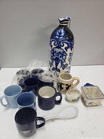 Overview of all ceramic items including mugs, vase, small containers and trinket box showing lot contents