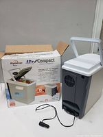 Koolatron 12V Compact Cooler/Warmer unit shown next to its original box with clear branding and usage instructions visible.