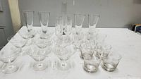 Wide shot showing various types of clear glass stemware arranged on white surface