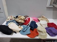 Photo of multiple hats showing a variety of styles and colors arranged on a table