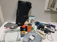 A wide view of assorted health and beauty items including leg brace, neck pillow, hair dryer, curling iron, digital scale, and other accessories.