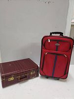 Two suitcases side by side, a red travel rolling suitcase and a reddish brown vintage suitcase.