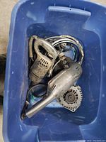 View of handheld drill, alternator, grinder parts and cords inside a blue plastic bin