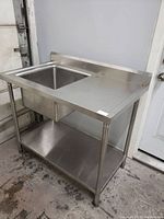 Front view of stainless steel work table with sink and lower shelf
