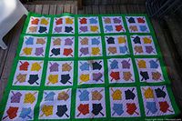 Full view of the colorful patchwork children's blanket laid out flat, showing the repeating pattern and green borders.