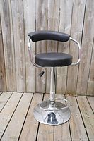 Side view of the barstool showing padded seat and backrest with chrome frame and pedestal base with footrest.