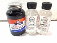 Photo of Elmer's No-Wrinkle Rubber Cement 8 oz with two bottles of Gamblin Gamsol 125 ml in clear bottles with black caps.
