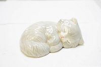 Angled view of grey sleeping cat figurine showing curled pose and facial details