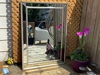 Front view of the vintage rectangular mirror with mirrored frame placed outdoors showing its reflective surface and minor edge scratches.