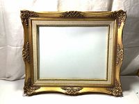 Full view of the antique gold tone wooden ornate carved frame with a rectangular opening inside.