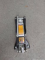 Top view of a Black Jack 2.5 ton hydraulic car jack lying on concrete surface.