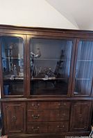 Front view of large mahogany wood dining room hutch showing glass doors on upper section, drawers and cabinets below.