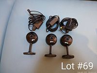 Three Geeni indoor WiFi security cameras with power cables on light blue surface.