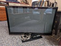Front view of the LG 42 inch plasma HDTV showing screen, frame, remote control, and power cord.