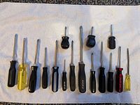 Photo showing 13 Phillips screwdrivers arranged in a row, various handle colors including black, yellow and red, different shaft lengths and thicknesses.
