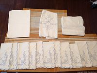 Photo showing three orange and beige striped placemats underneath white cloth napkins and a white and blue embroidered table runner