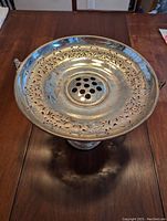 Top view of silver flower vase showing perforated holes for individual flowers and decorative cut-out edge.