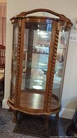 Front view showing entire curved oak display cabinet with barley twist columns and glass shelves