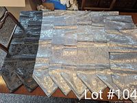 Photo of six silver and two black table runners laid out on a wooden surface showing their damask pattern and pointed ends.