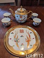 Photo showing the entire Chinese wedding teaset including teapot, serving plate, and four teacups with gold detailing and traditional motifs.