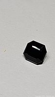 Top view of the octagon cut deep forest green tourmaline gemstone showing faceting and color.