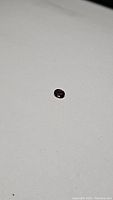 Close-up photo of deep purple-red oval sapphire, 0.63 carat, showing gemstone color and cut.
