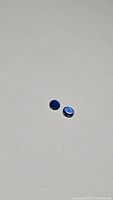 Two small round royal blue kyanite gemstones on a plain white background.