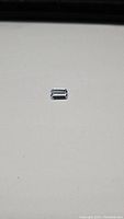Emerald cut aquamarine gemstone placed on a white background, clearly showing the cut and light blue color.